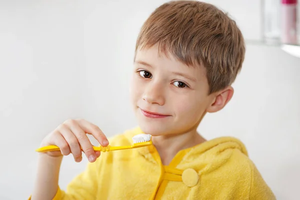 Niño pequeño en albornoz lavándose los dientes después del baño de noche — Foto de Stock