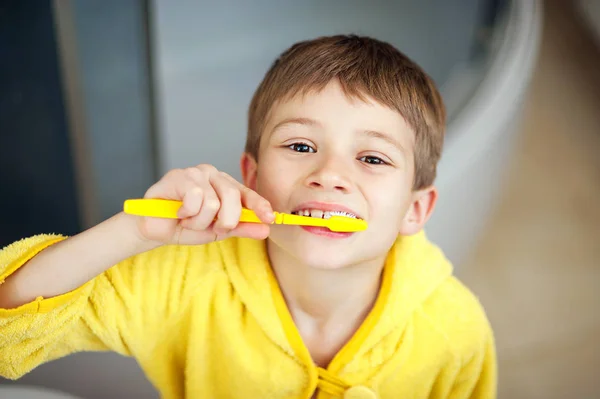Chico cepillándose los dientes en la bañera, sonriendo. concepto de estilo de vida saludable — Foto de Stock