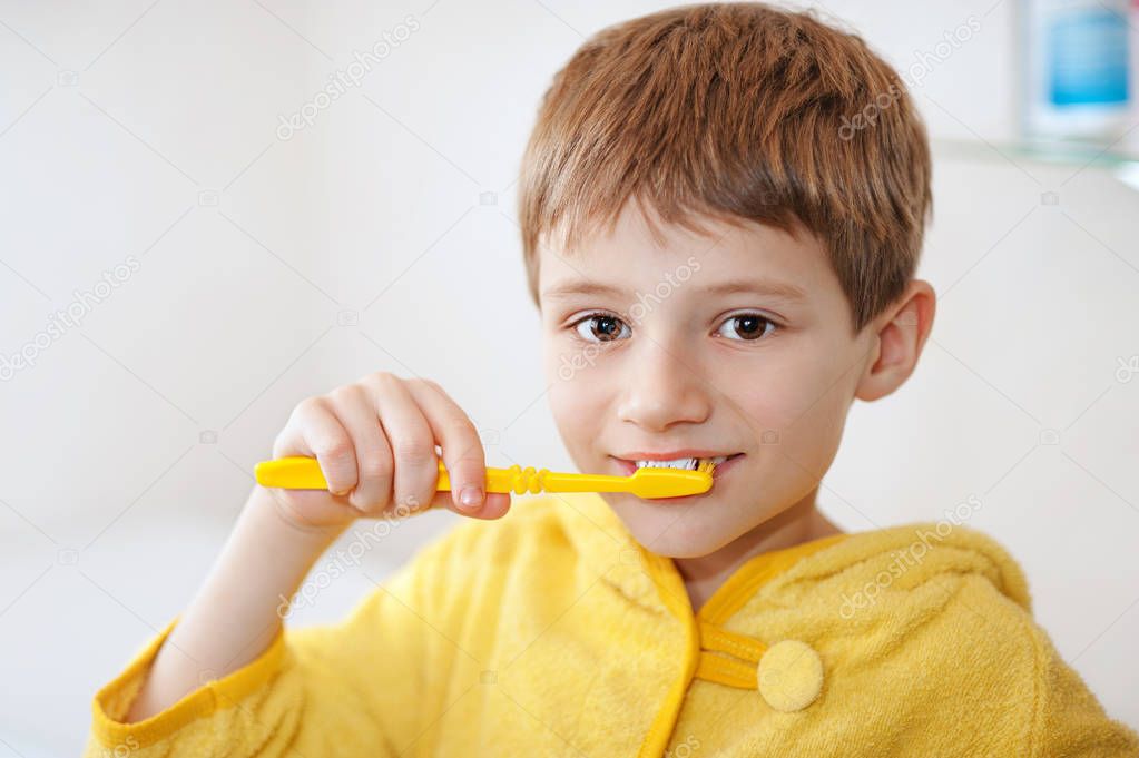 little baby boy in yellow bathrobe with tooth brush