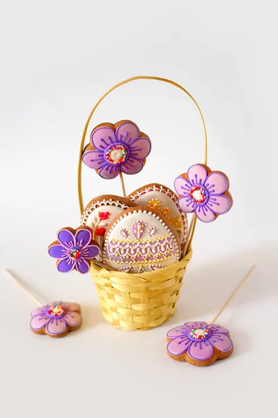 La pequeña Pascua está en una bufanda festiva. Huevos de Pascua multicolores yacen en una cesta con decoración de pan de jengibre —  Fotos de Stock