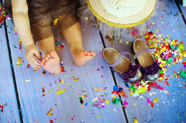 Kid blote voeten benen in tegen de confetti en slingers - selectieve aandacht, kopie-ruimte — Stockfoto