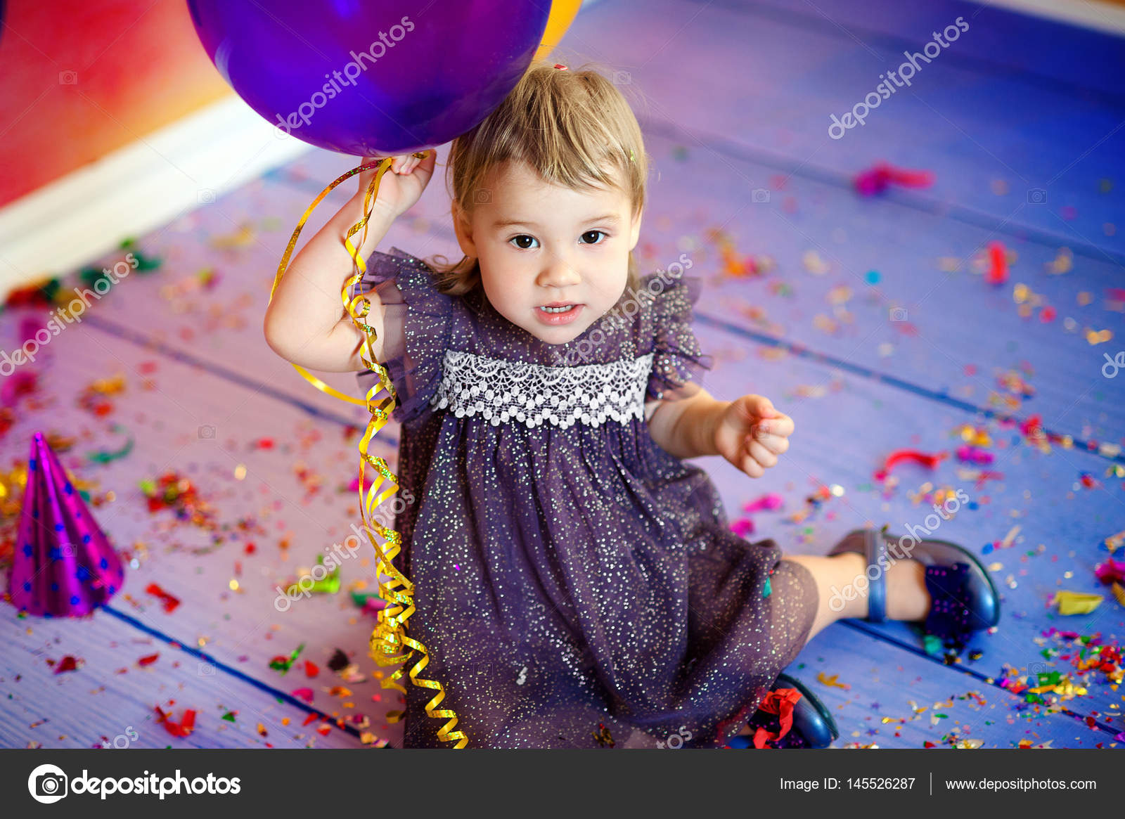 Linda niña de 1-2 años sentada en el suelo con globos rosados en