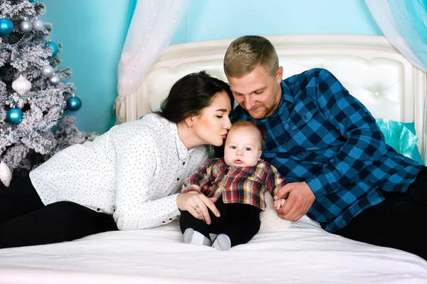 Felicidade familiar - os pais beijam seu bebê recém-nascido em uma árvore de Natal — Fotografia de Stock