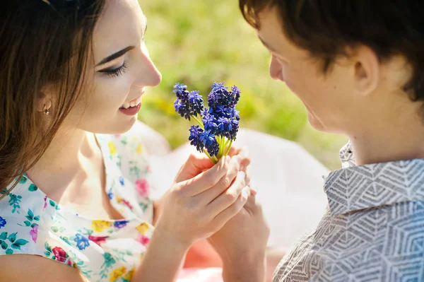 Pareja joven enamorada besándose y abrazándose a las flores azules. De cerca. — Foto de Stock