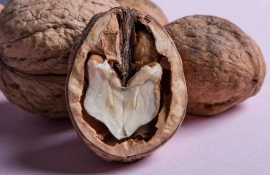 Pembe arka planda bütün ve doğranmış ceviz.