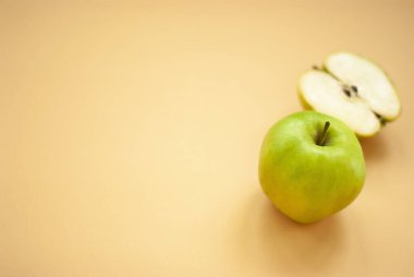 Kesme tahtası ve yeşil elmalar açık sarı mutfak havlusunda sol tarafta fotokopi alanı, sarı arka plan. Üst Görünüm