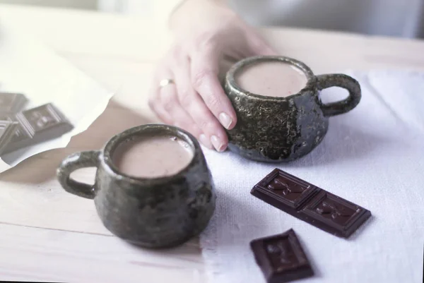 Mano de mujer sosteniendo una taza de cacao en la mañana en casa, junto a una segunda taza para un compañero. Fondo claro . — Foto de Stock