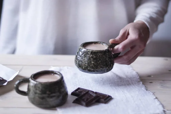 Mano de mujer sosteniendo una taza de cacao en la mañana en casa, junto a una segunda taza para un compañero. Fondo claro . — Foto de Stock