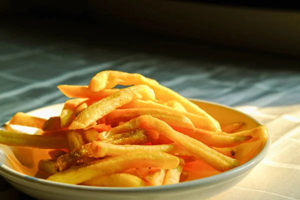 Beyaz tabakta kızarmış patates kızartması. Kumaş arkaplanındaki resmin kapatılması.