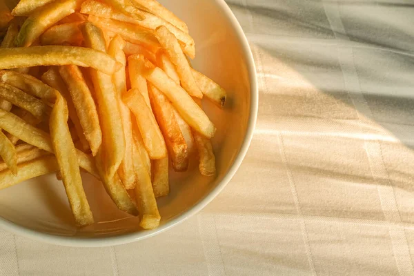 Beyaz tabakta kızarmış patates kızartması. Kumaş arkaplanındaki resmin kapatılması.