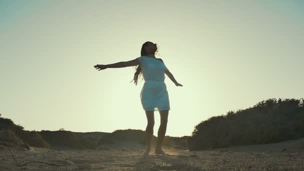 Girl in white dress girl whirling at sunset background. Desert. Slow motion. — Stock Video