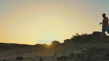 Tepeden aşağı yürüyüş erkekler. Gün batımı siluet.