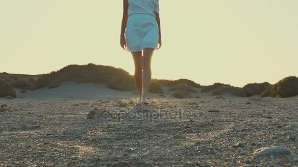 Ragazza in abito bianco a piedi dal tramonto alla macchina fotografica. Deserto . — Video Stock