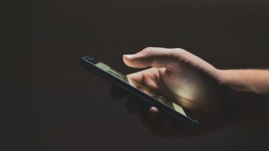 Genç adam closeup yazarak sms resimleri telefon kaydırma eller. Gece.