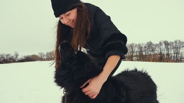 Unga kvinnor leker med hunden i snön. Vinter. — Stockvideo