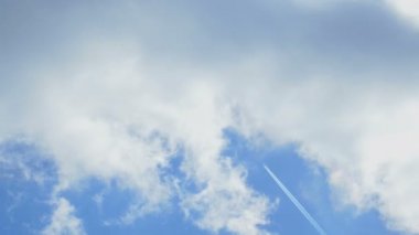 Uzak bir uçak Tepegöz, yüksek bir jet contrail bulutlu bir mavi gökyüzü karşı bırakarak geçer. Rüzgarlı
