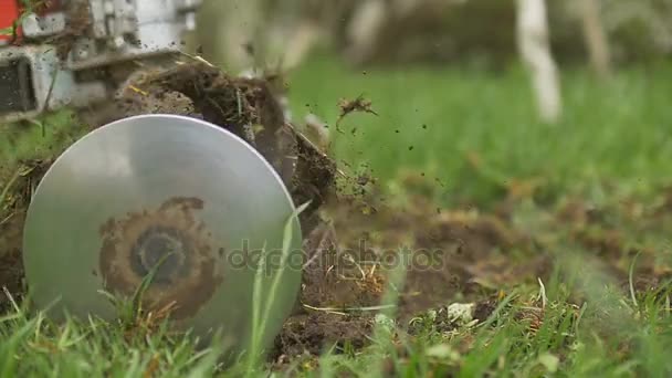 Close-up van hand motor opzijschuiven mes gooien grond en gras. Slow motion — Stockvideo