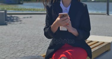 Kadın bir cep telefonu ve içecek kahve dışarıda parkta tarama