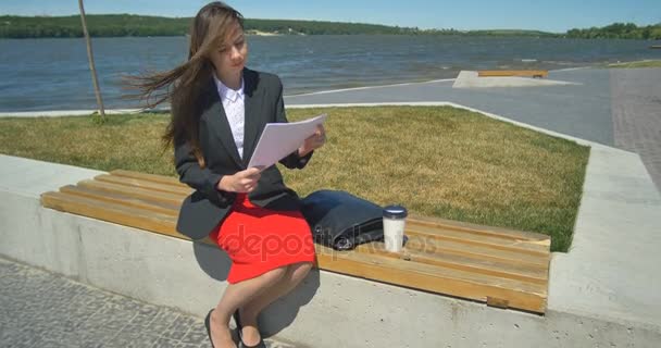 Attraktive Geschäftsfrau liest im Park — Stockvideo