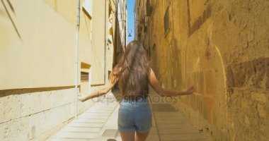 Güneşli bir günde küçük Caddede yürüyen genç turist kadın. Ortaçağdan kalma eski şehir keşfetmek Avrupa'da tatil harcama kız.