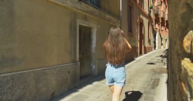 Güneşli bir günde küçük Caddede yürüyen genç turist kadın. Ortaçağdan kalma eski şehir keşfetmek Avrupa'da tatil harcama kız.
