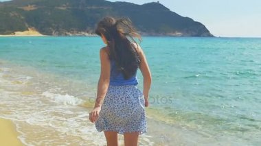 Çekici kadın çalışan kumlu plaj boyunca. Açık mavi su ağır çekim