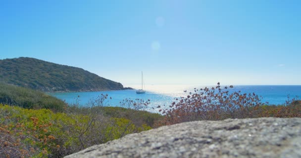 Onde che atterrano su spiaggia di pietra. Yacht all'orizzonte. Acqua cristallina blu . — Video Stock