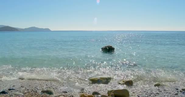 Κύματα προσγείωση στην παραλία της πέτρας. Καταγάλανα νερά. — Αρχείο Βίντεο