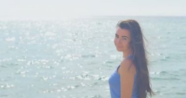 Plajı'nda kadın portresi. Güneşli Plaj ve açık mavi su. Ağır çekim.