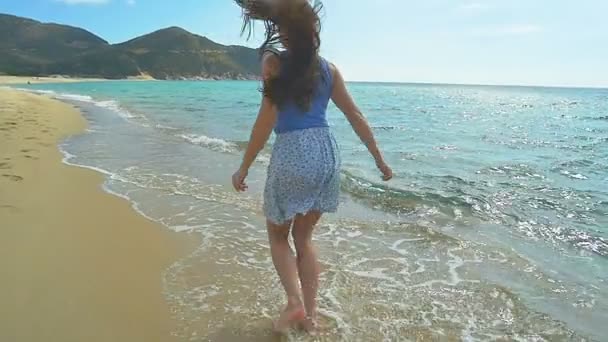 Привлекательная женщина бегает вдоль песчаного пляжа. Медленное движение чистой голубой воды — стоковое видео