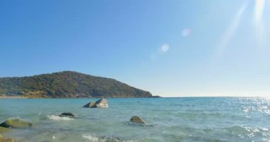 Taş kumsalda açılış dalgalar. Açık mavi su.