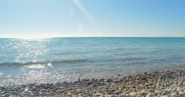 Хвилі приземляються на кам'яному пляжі. Прозора блакитна вода . — стокове відео