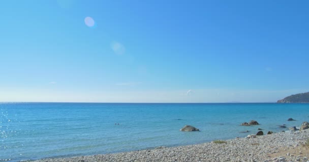 Golven landing op stenen strand. Helder blauw water. — Stockvideo