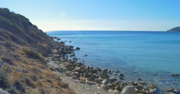 Волны высаживаются на каменный пляж. Чистая голубая вода . — стоковое видео