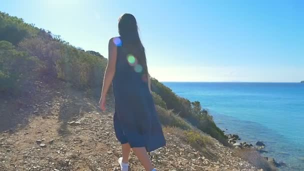 Das junge Mädchen hat die Hände auf dem Hügel über dem Meer erhoben. klares Meer blaues Wasser. — Stockvideo