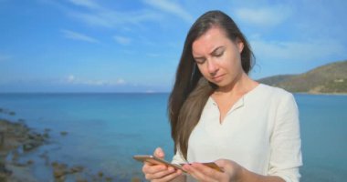 Tatil alışveriş online cep telefonu açık mavi deniz arka plan ile kredi kartı kullanan kadın