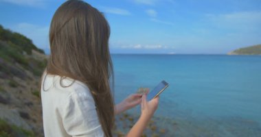 Tatil alışveriş online cep telefonu açık mavi deniz arka plan ile kredi kartı kullanan kadın