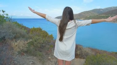 Genç kız Eller yukarı hill adlı deniz üzerine yükseltti. Açık deniz mavi su.