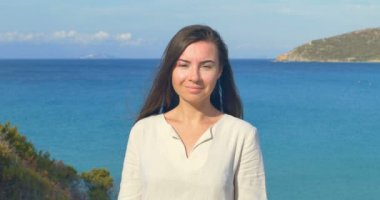 Güzel genç kadın çalışan el Akdeniz sahil arka plan üzerinde rüzgar esiyor saçlarının arasından portresi.