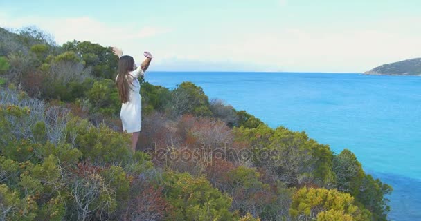 Den unga flickan har uppväckt händer på hill över havet. Klara blå havsvatten. — Stockvideo