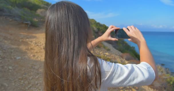 Mujeres atractivas haciendo fotos de mar con smartphone. Colinas y agua azul clara . — Vídeo de stock