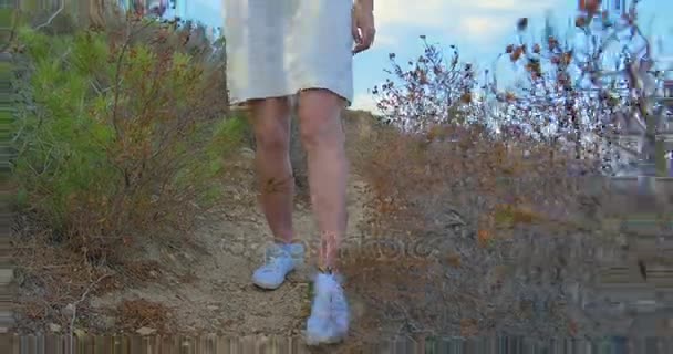 Güzel kadın bacaklar beyaz spor ayakkabı, taşlı zemin boyunca gidiyor. Çölde yürürken. — Stok video