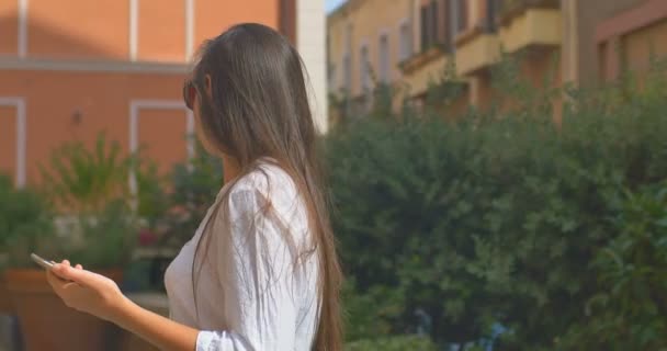 Vrouw toeristische in zonnebril is op zoek naar een adres met een Gps navigator op een smartphone — Stockvideo