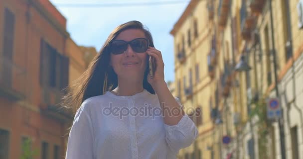 Nő beszél a mobiltelefon, a régi európai városban Steadicamnél lövés — Stock videók