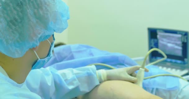 Ένας γιατρός χρησιμοποιεί σύγχρονες ηχόγραμμα να προβάλετε φλέβα στην σκληροθεραπεία διαδικασία. Μια καινοτόμο μέθοδο Εξωγκόμενος φλέβες χειρουργική επέμβαση, γκρο πλαν — Αρχείο Βίντεο