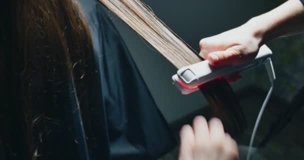 Женские руки делают операцию по спасению волос. Электрический инструмент регенерации волос с красным неоновым светом — стоковое видео