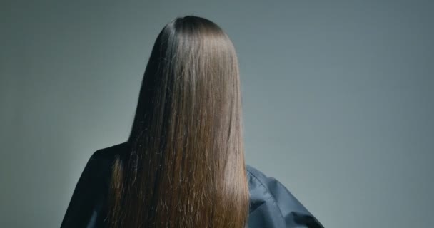 Vista posterior de la mujer morena jugando con su pelo sobre fondo claro — Vídeo de stock