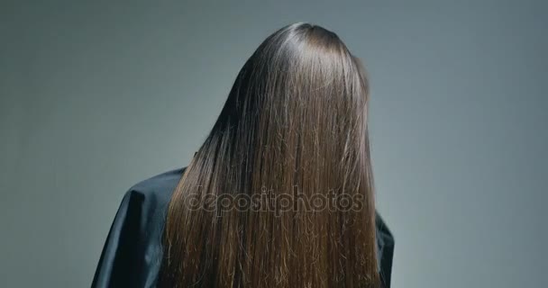 Vista posterior de la mujer morena jugando con su pelo sobre fondo claro — Vídeos de Stock