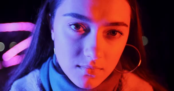 Mooie brunette vrouw in rood en blauw neon licht 's nachts. Fashion model meisje met make-up en cirkel oorbellen in kleurrijke verlichting — Stockvideo