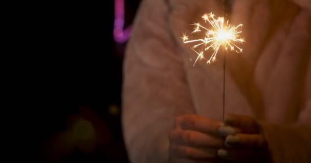 Sparklers in handen van jonge vrouwen. Vonken verstrooit in verschillende richtingen op neon lichten achtergrond — Stockvideo